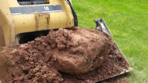 Excavation - Rock removal with boulder in small Caterpillar front end loader bucket
